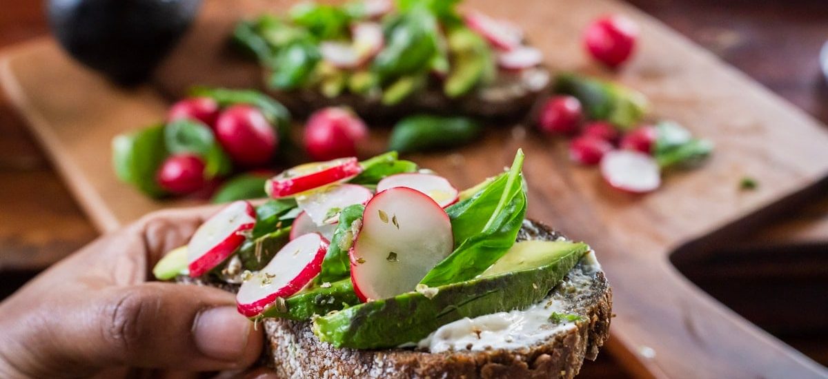 person holding bread with vegetable and cream
