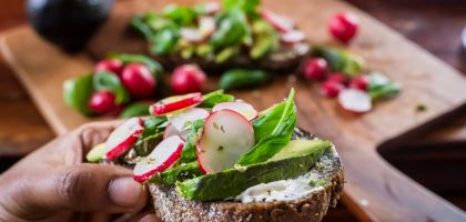 person holding bread with vegetable and cream