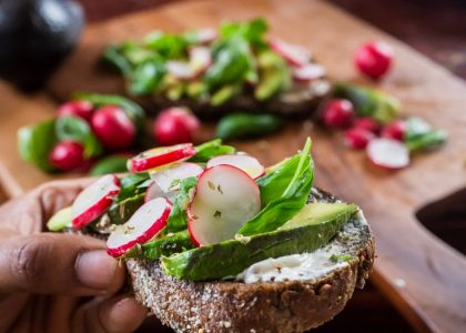 person holding bread with vegetable and cream