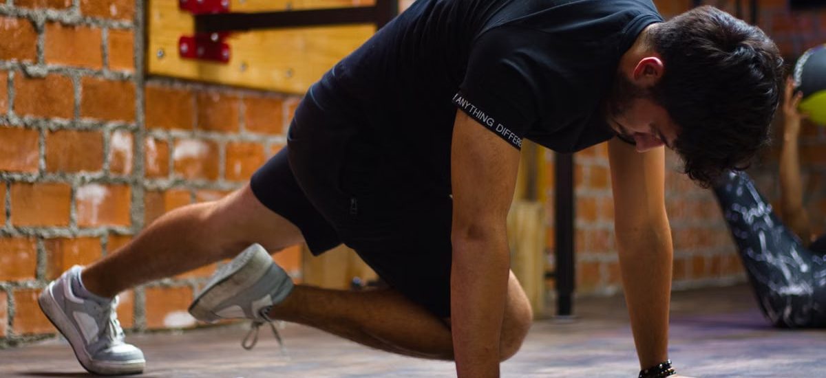 Man working out indoors, performing push-up exercise against a brick wall.